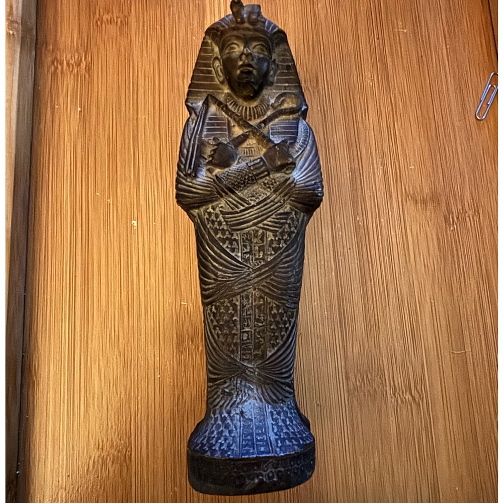 A miniature replica of an Egyptian sarcophagus containing a mummy figurine.